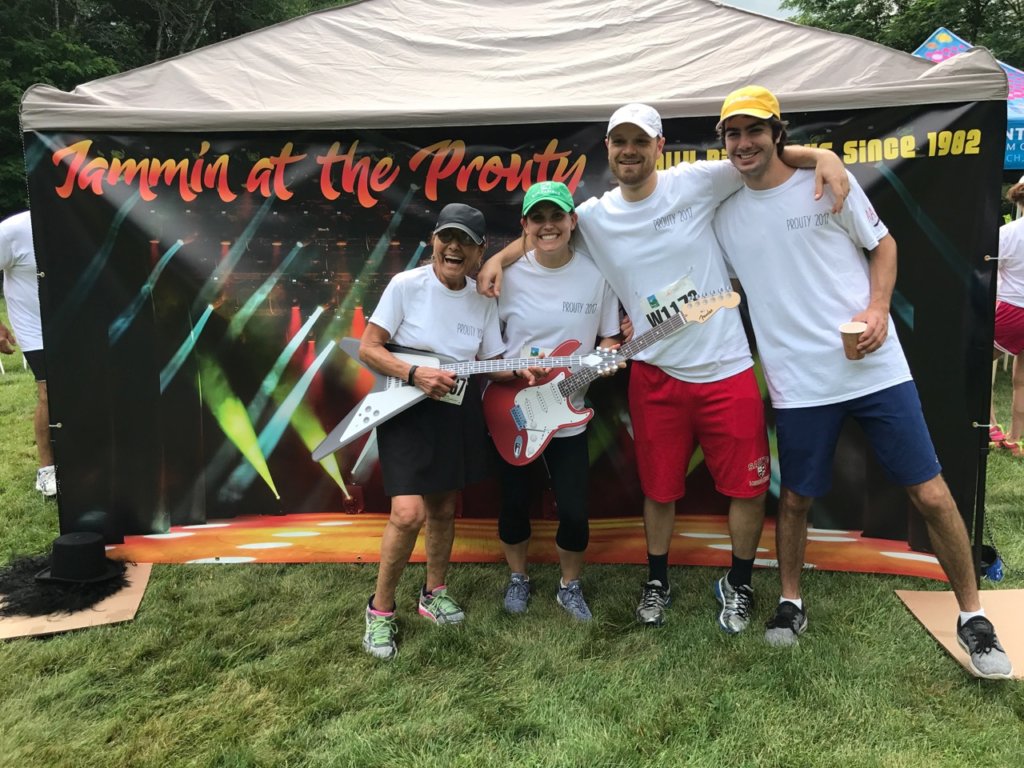 four people standing by a tent smiling at the camera with guitars