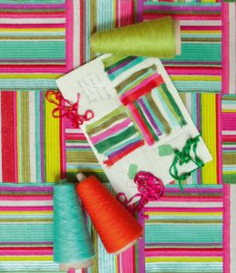 bright striped fabric from above with thread and design swatches