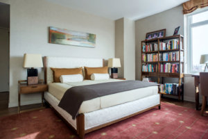 view of a bedroom with a bookshelf and maroon carpet