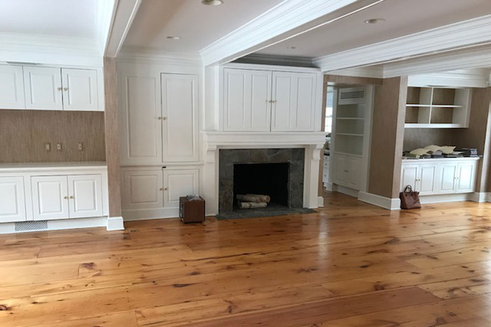 empty great room with wood flooring and white built in cabinets